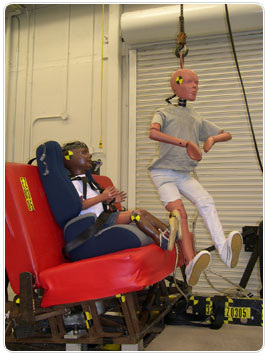 Child-size test dummy gets lifted into the bus seat to test Safety Angel &reg; products.